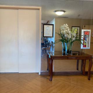 A lobby area featuring an elevator, a decorative table with flowers, and framed artwork on the wall.