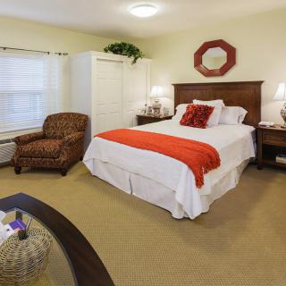 A cozy bedroom with a neatly made bed, armchair, and warm lighting.