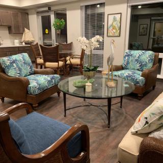 A cozy living room with a seating arrangement featuring colorful armchairs, a glass coffee table, and decorative plants.