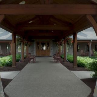 A wooden entrance pathway leading to a building, surrounded by gardens.