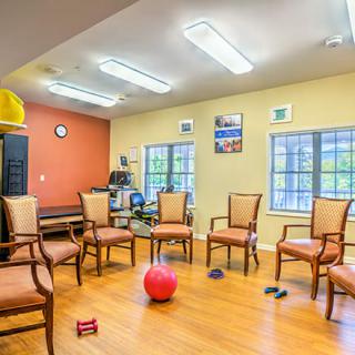 A therapy or meeting room with chairs arranged in a circle, featuring exercise equipment on the floor.