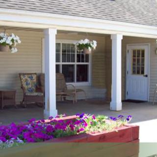 A cozy porch with chairs, floral decorations, and a welcoming entrance.