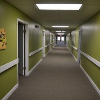 A long indoor corridor with green walls and multiple doors.