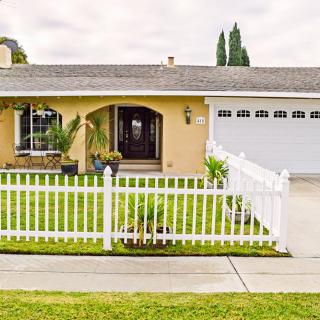 A cozy single-story house with a white picket fence and well-maintained front yard.