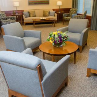 A cozy waiting room with comfortable chairs and a table adorned with a flower arrangement.