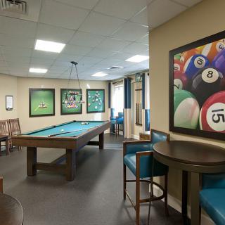 A spacious game room featuring a pool table and vibrant billiards-themed artwork.