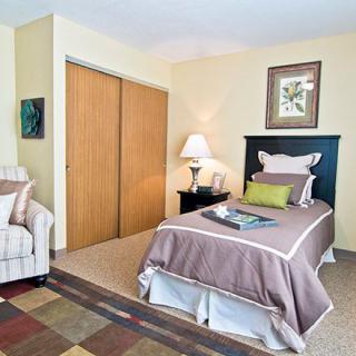 A cozy bedroom with a single bed, armchair, and elegant decor.