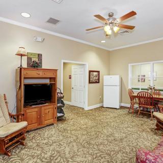 A cozy living room with a TV stand, ceiling fan, and dining area.