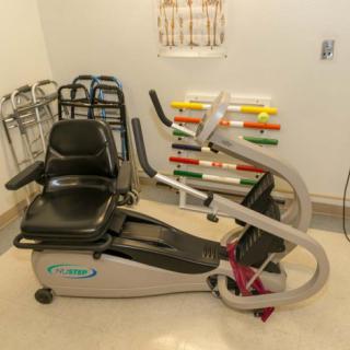 A stationary bike in a rehabilitation room with various fitness equipment.