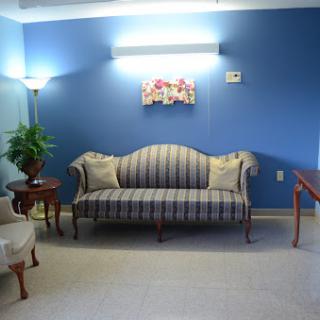 A cozy living room setup featuring a striped sofa, a small table, and a potted plant against a blue wall.