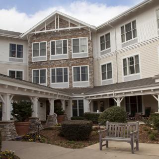 A three-story residential building with landscaped courtyard and benches.