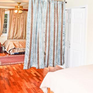 A cozy bedroom with hardwood flooring and curtains separating the space.