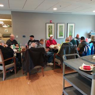 A group of people gathered around a table for a discussion in a cozy indoor setting.
