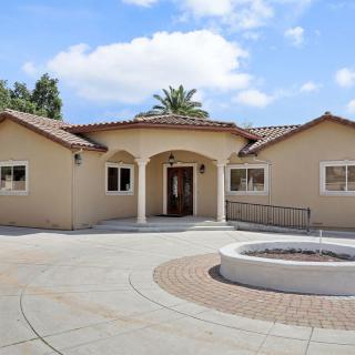 A suburban house with a circular driveway and a clear blue sky in the background.