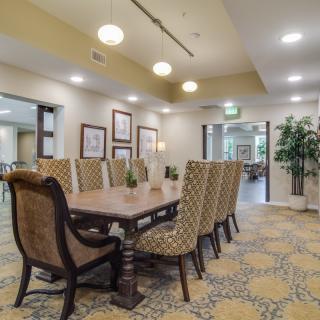 A well-appointed dining room with a long wooden table and upholstered chairs, featuring elegant interior design elements.