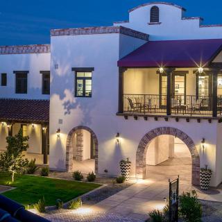 A beautiful Spanish-style house with a well-lit exterior and arched design elements.