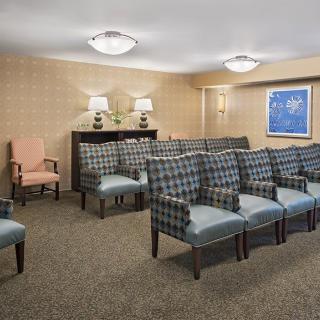 A neatly arranged room with rows of upholstered chairs, soft lighting, and wall decor.