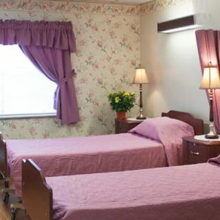 A cozy bedroom with twin beds, pink bedding, and floral wallpaper.