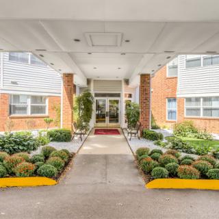 A well-maintained building entrance with landscaping and a paved walkway.
