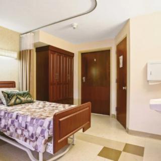 A clean and organized hospital room with a single bed.