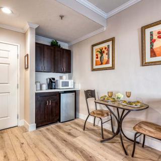 A cozy kitchenette with a small dining area, featuring a microwave, mini fridge, and wall artwork.