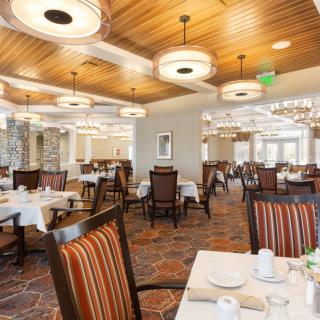 A modern restaurant dining area with neatly arranged tables and stylish lighting fixtures.