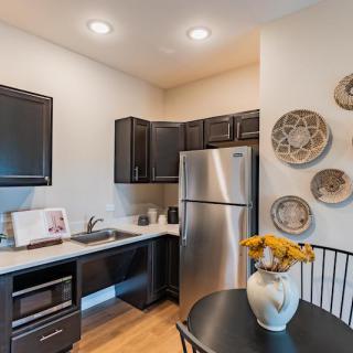 A modern kitchen with dark cabinetry, stainless steel appliances, and decorative elements on the wall.