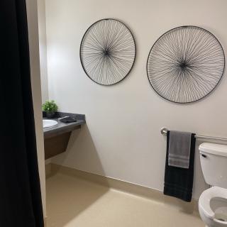 A modern bathroom featuring minimalist decor with two circular wall artworks, a sink, and neatly arranged towels.