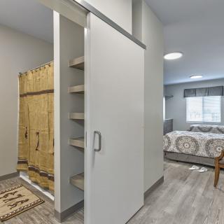 A modern, minimalist bedroom with a sliding door and built-in shelving unit.