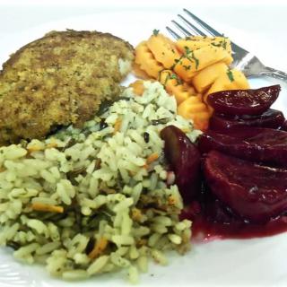 A plate of food featuring seasoned chicken, rice with herbs, roasted vegetables, and a side of cooked beets.