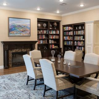 A cozy dining area with a large table, surrounded by bookshelves and a fireplace.