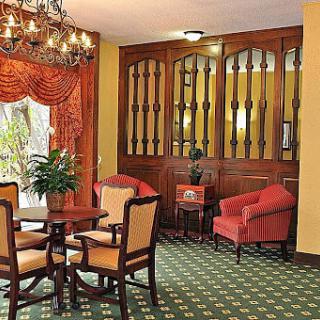 A classic-style interior featuring a seating area with upholstered chairs and a round table, illuminated by an elegant chandelier.