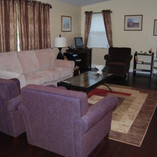 A cozy living room with a sofa, armchair, and coffee table, complemented by warm-toned curtains and decor.