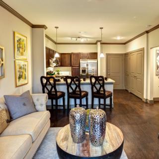 A modern apartment interior featuring a cozy living room and an open kitchen with bar seating.