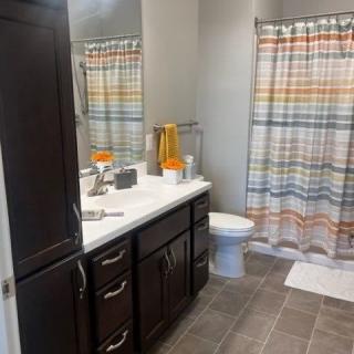 A modern bathroom with a sink, toilet, and colorful striped shower curtain.