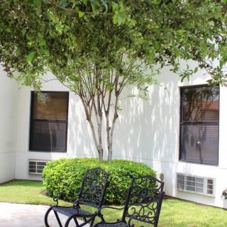 A peaceful outdoor area with benches under a tree near a building.