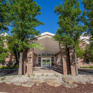 A building entrance surrounded by trees and landscaping.