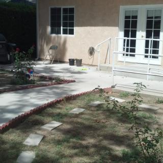 A backyard patio with a garden pathway leading to the house.