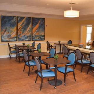 A dining area with multiple tables and chairs, decorated with artwork on the wall.
