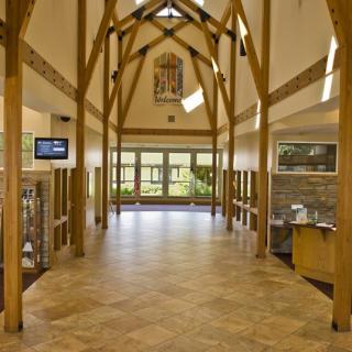 A spacious, well-lit hallway with wooden beams and large windows.