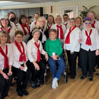 A joyful group of choir members dressed in white shirts and red scarves, gathered together for a special performance.