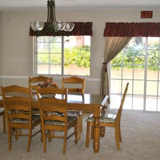 A dining room with a wooden table set and large windows letting in natural light.