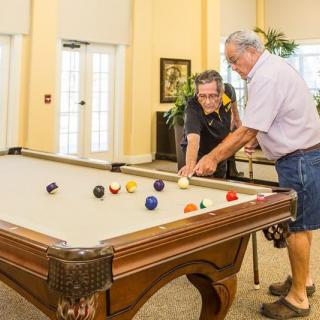 Two men playing a game of billiards on an indoor pool table.