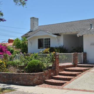 A charming suburban home with a well-maintained garden and brick steps leading to the entrance.