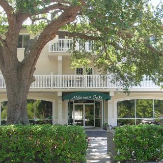 A residential building with a tree-lined entrance and green awning.