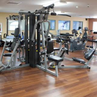 A spacious gym with various exercise equipment, including a multi-gym machine, on a wooden floor.