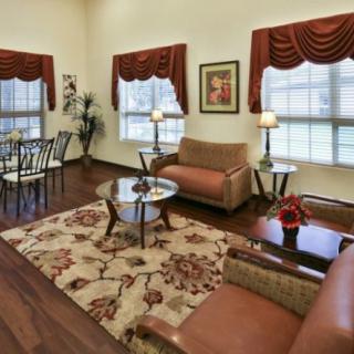 A cozy living room with a sofa, coffee table, and dining area featuring warm decor and wooden flooring.