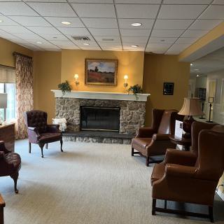 A cozy living room with comfortable armchairs arranged around a stone fireplace, complemented by warm lighting and tasteful decor.