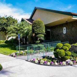 A well-maintained building entrance with lush landscaping and a curved pathway.