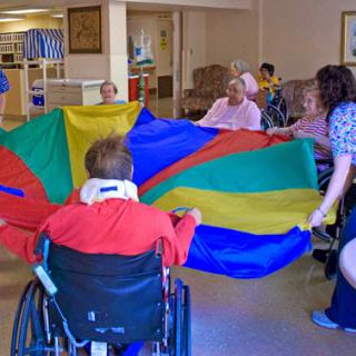 Seniors engaging in a fun parachute activity at a care facility.